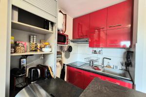 a red kitchen with a sink and red cabinets at Cozy apartment "WAPITI" at the foot of the slopes in Les Déserts +38 photos