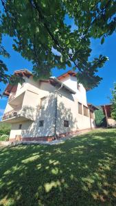a large white building with a green lawn at Hidden Haven Cottage Sarajevo in Lokve +12 photos