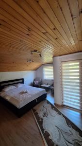 a bedroom with a bed and a wooden ceiling at Hidden Haven Cottage Sarajevo in Lokve