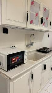a white kitchen with a microwave on a counter at نسمة كيان للشقق المخدومة Nasma Kayan Serviced Apartments in Jeddah +48 photos
