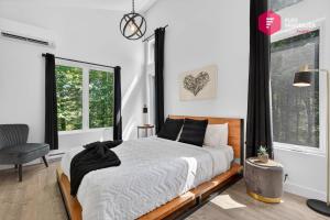 a bedroom with a bed and a chair and windows at L'Azur de Portneuf - Chalet lumineux avec spa et véranda à Pont-Rouge - Resort près de Québec in Pont-Rouge