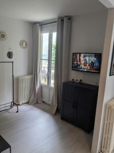 a living room with a television and a window at Studio 4 personnes in Eaux-Bonnes