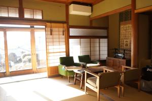 a living room with a table and chairs and windows at Guest House Toranjyo-lit in Tamano