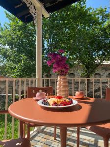 a table with a plate of food and a vase of flowers at Zhorzholiani House - Betkili in Lakhiri