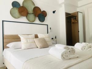 a large white bed with white pillows and hats on the wall at Antigua 22 in Monopoli