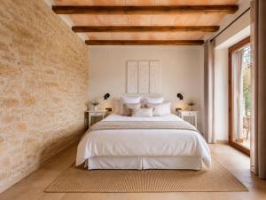 a bedroom with a white bed and a brick wall at El Gresol - Naturaleza y Relax in Senant