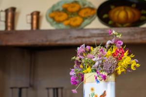 a bucket full of flowers on a counter with a pumpkin at Le ginestre 10 in Murlo +10 photos