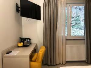 a room with a desk with a yellow chair and a window at Appart-Hotel Gwendy in Bour +177 photos
