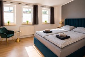 a bedroom with a bed and a chair and windows at Hotel & Restaurant Hasa in Gernrode - Harz