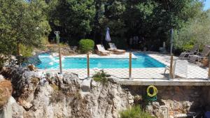 a swimming pool with a rock wall next to at Les Robinsons in Sillans-la Cascade +8 photos