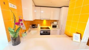 a kitchen with yellow tiles and a vase of flowers on a counter at Seaside one bedroom apartment with terraces, garage & swimming pool in Cascais