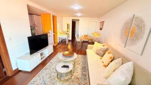 a living room with a couch and a tv at Seaside one bedroom apartment with terraces, garage & swimming pool in Cascais