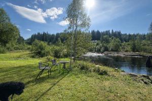 two chairs and a table next to a river at Turifoss Camping Cabin 2 in Svedjan