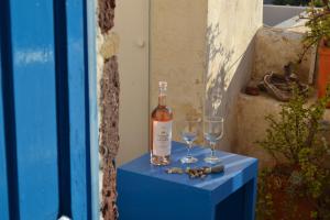 a bottle of wine and two glasses on a blue table at Kalleni Santorini in Emporio +44 photos
