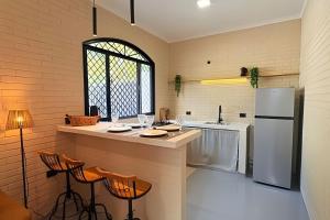 a kitchen with a counter and a refrigerator at 2 Suítes com Ar e Cozinha Completa in Andradina