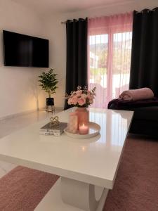 a white table with a vase of flowers on it at Villa Azar in Dobra Voda