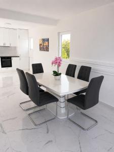 a white dining room with a white table and black chairs at Villa Azar in Dobra Voda
