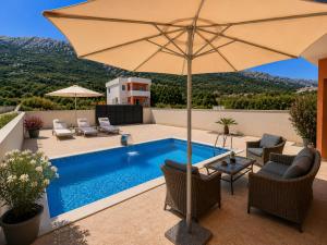 a patio with an umbrella and a swimming pool at Villa Azar in Dobra Voda