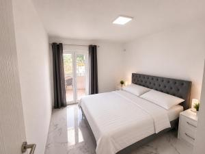 a white bedroom with a large bed and a window at Villa Azar in Dobra Voda
