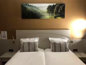 a bedroom with two beds with white sheets and pillows at Appart-Hotel Gwendy in Bour