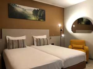 a bedroom with two beds and a chair and a mirror at Appart-Hotel Gwendy in Bour