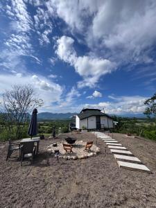 a building with a table and chairs and an umbrella at Green Valley a 5 min de Xielo Paracaidismo,la pista secreta y Paintball rural Leticia in Ricaurte