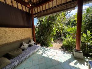 a couch on the side of a porch with trees at Kanda Homestay in Sidemen +53 photos