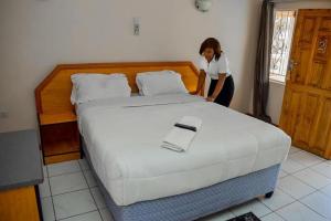 a woman is standing next to a large bed at Mana Nest Lodge in Choma