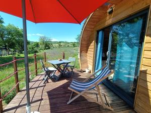 a deck with a table and chairs and an umbrella at Tiny house chez Manou in Castelnau-de-Mandailles