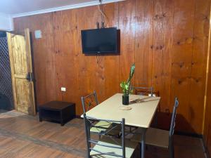 a dining room with a table and a tv on a wooden wall at Pumakari Rapa Nui in Hanga Roa