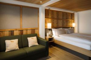 a bedroom with a bed and a green couch at Adler Adelboden in Adelboden +24 photos