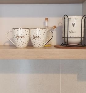 two coffee cups sitting on a wooden shelf at Green Apartman in Čukarica