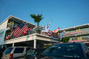 a building with american flags and cars parked in front at Grecian Garden Motel in North Wildwood
