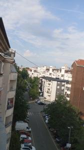a city street with parked cars and buildings at Green Apartman in Čukarica