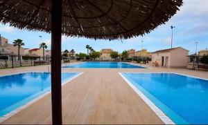 a pool with an umbrella and a swimming pool at Villa Banfield in Gran Alacant