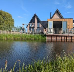 a house on a dock next to a body of water at B&B Het Houten Huis in Brandwijk