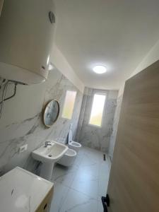 a bathroom with a sink and a toilet and a mirror at Leni Apartment in Patza-Kuqani