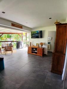 a living room with a tv and a wooden cabinet at BLUE DREAM SPA in Les Trois-Îlets