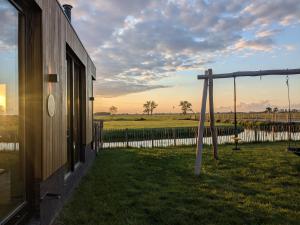 a swing in a yard next to a house at B&B Het Houten Huis in Brandwijk +16 photos