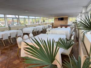 a room with white tables and white chairs and plants at New Venus in Curtea de Argeş