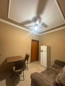 a living room with a ceiling fan and a table and a refrigerator at Hotel Matrin in Barretos