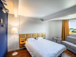 a hotel room with a bed and a couch at ibis budget La Roche Sur Yon Vendespace in Mouilleron-le-Captif