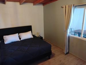 a bedroom with a black bed and a window at Casa Atitur in San Pedro de Atacama