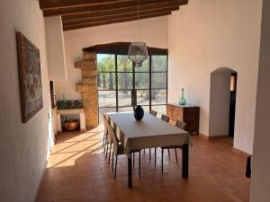 a dining room with a table and a large window at Villa S'erisal in Alaró