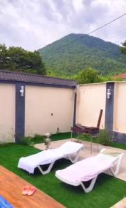a backyard with two beds and a table and chairs at Emaar Afreem Pastar Qebele in Gabala