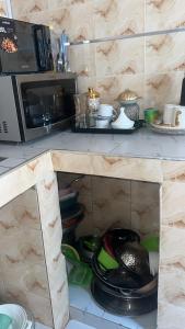 a kitchen counter with a shelf with dishes and a microwave at 2chambres salon villa Thierno sene in Niakoul Rap