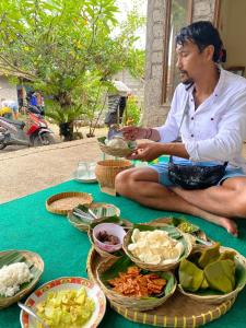a man sitting on the ground with plates of food at Kanda Homestay in Sidemen