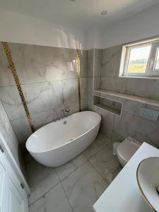 a white bathroom with a tub and a toilet at YDA Apartament's in Baciu