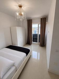 a bedroom with a white bed and a chandelier at YDA Apartament's in Baciu
