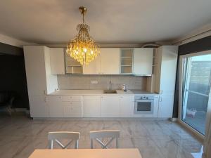 a kitchen with white cabinets and a chandelier at YDA Apartament's in Baciu